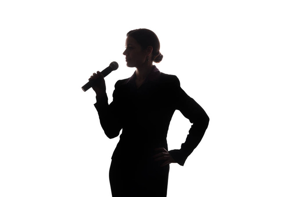 Νεαρή γυναίκα τραγουδάει στο μικρόφωνο, αυξάνοντας τα χέρια του - σιλουέτα - Φωτογραφία, εικόνα