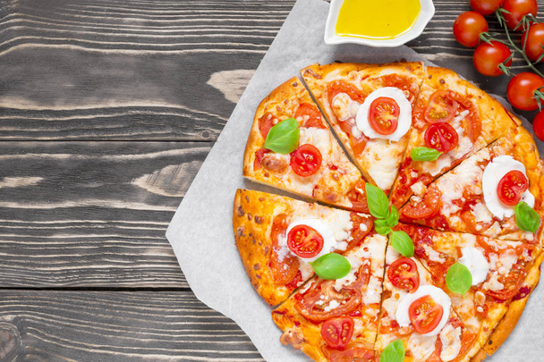 pizza casera en rodajas Margherita con tomates, albahaca, romero y queso mozzarella
 - Foto, Imagen