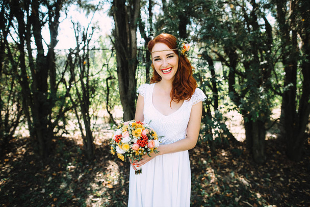 Red-haired bride holding a wedding bouquet and laughing - Foto, immagini