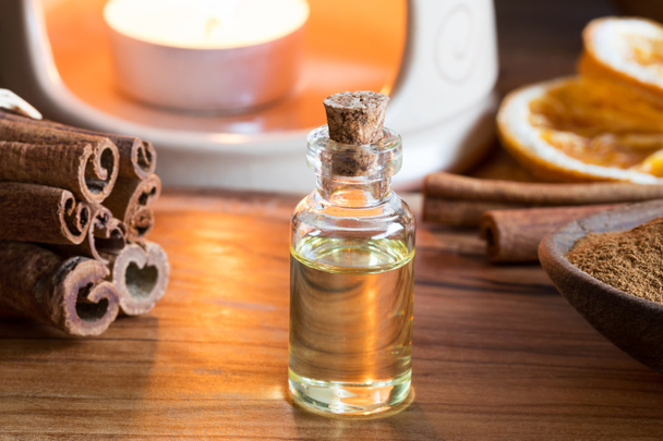 Una botella de aceite esencial de canela con varillas de canela y una lámpara de aroma
 - Foto, imagen