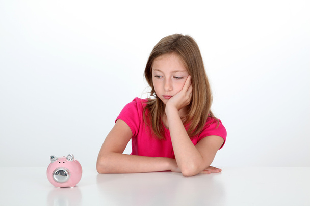 Portrait of young girl looking at piggy bank - Fotografie, Obrázek