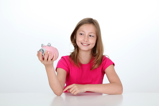 Smiling young girl holding piggy bank - Valokuva, kuva