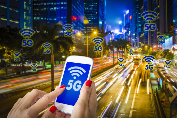 Compuesto digital de 5G, una mano de mujer usando un teléfono inteligente con ciudad moderna borrosa en el fondo. Ciudad ocupada de Hong Kong y concepto de tecnología web móvil de alta velocidad
. - Foto, imagen