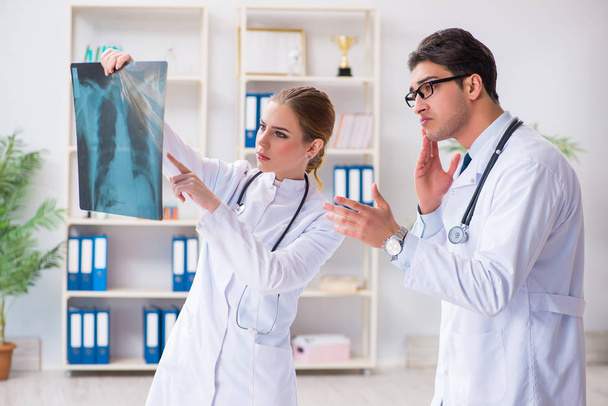Два врача осматривают рентгеновские снимки пациента на предмет диагностики - Фото, изображение