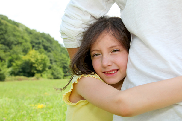 klein meisje zetten haar armen rond de taille van haar vader - Foto, afbeelding