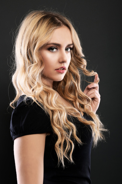 Blonde girl with long and volume shiny wavy hair . Beautiful woman model with curly hairstyle . - Photo, image