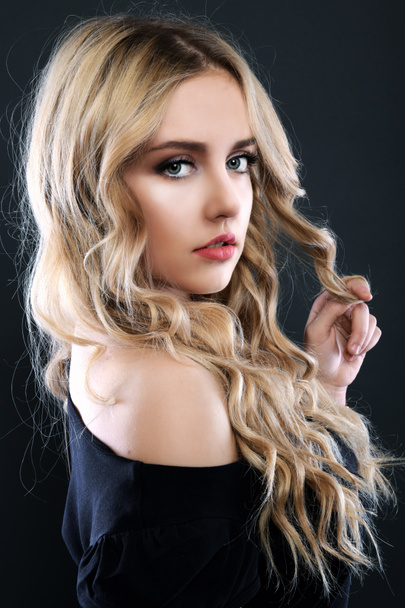 Блондинка з довгим і об'ємним блискучим хвилястим волоссям. Красива жінка модель з кучерявою зачіскою
 . - Фото, зображення