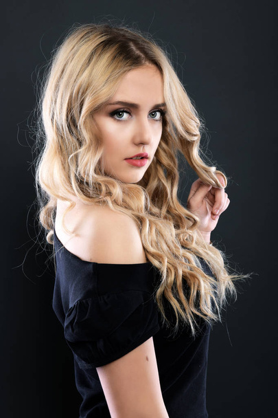 Blonde girl with long and volume shiny wavy hair . Beautiful woman model with curly hairstyle . - Foto, imagen
