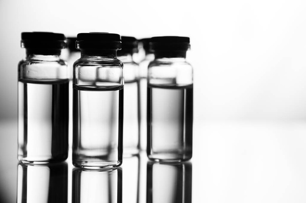 Groepsobject voor vloeibare geneesmiddelen agent in helder glaswerk in medisch laboratorium. Aantal ampullen met een transparante geneeskunde in medische laboratorium - Foto, afbeelding