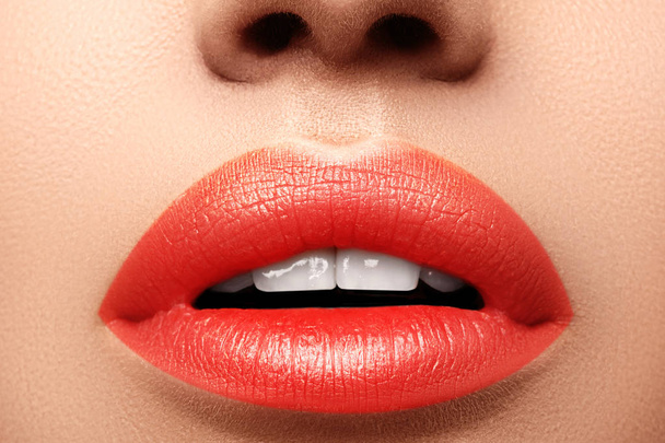 Macro close-up shot van vrouwelijke mond. Sexy Glamour red lips make-up met sensualiteit gebaar. Oranje kleur, volle lippen - Foto, afbeelding