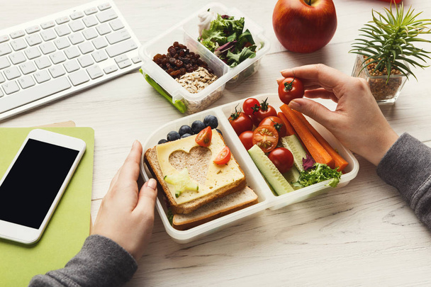 Жінка їсть здоровий бутерброд з обідньої коробки за її робочим столом
 - Фото, зображення