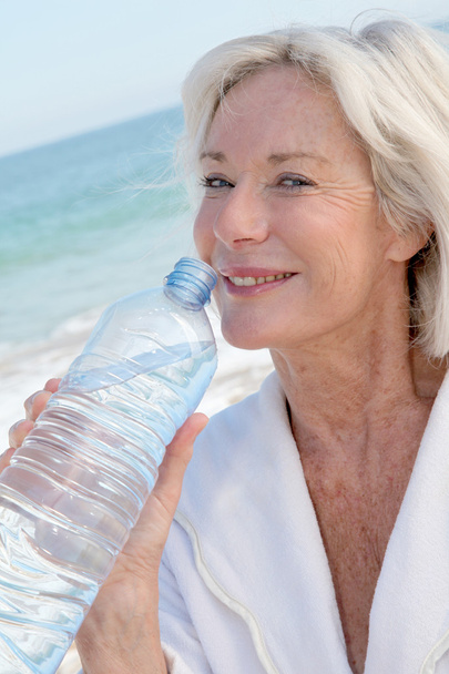 Senior woman drinking water from bottle - Photo, image