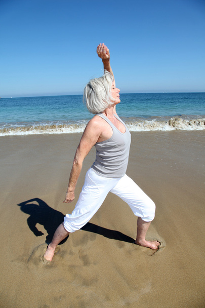 Senior woman doing stretching exercises on the beach - Photo, Image