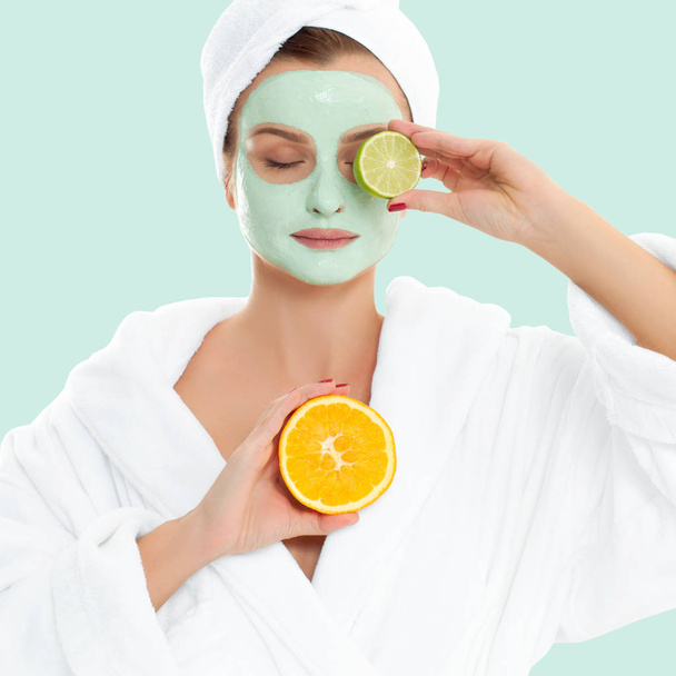 Beautiful woman with clay mask on pastel green background. Beauty and spa - Fotó, kép