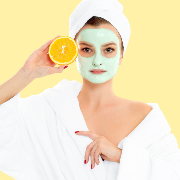 Beautiful woman with clay mask on pastel yellow background. Beauty and spa - Foto, immagini