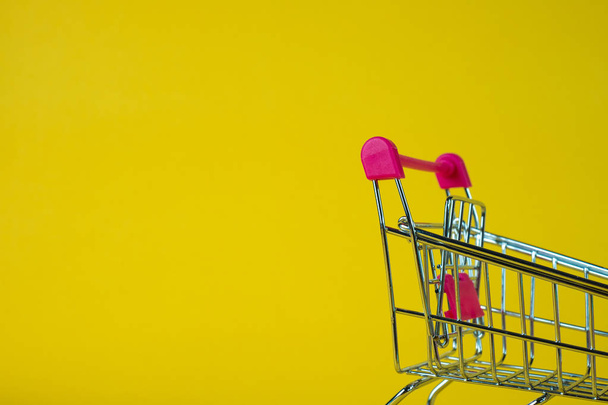 Shopping cart or supermarket trolley on yellow background, business finance shopping concept idea. - Фото, изображение