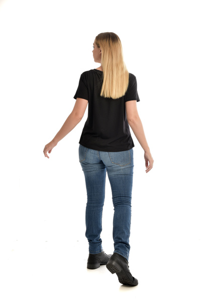 full length portrait of blonde girl wearing simple black shirt and jeans. standing pose facing away from camera, isolated on white background. - Fotografie, Obrázek