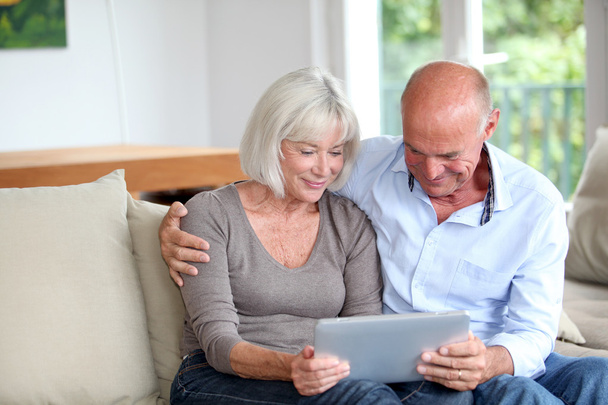 Senior couple using electronic tablet at home - Fotó, kép