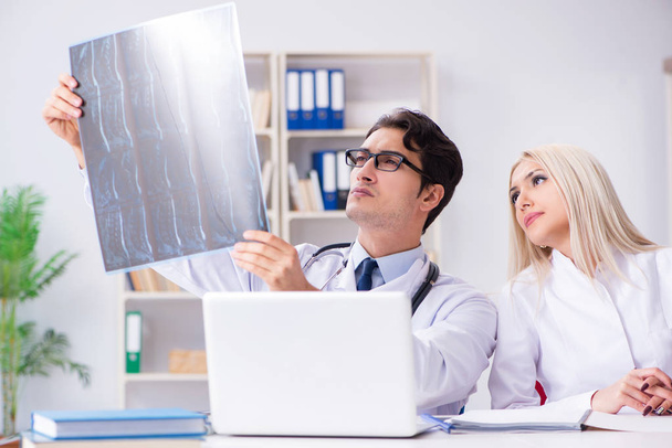 Dwóch lekarzy badających zdjęcia rentgenowskie pacjenta w celu rozpoznania - Zdjęcie, obraz
