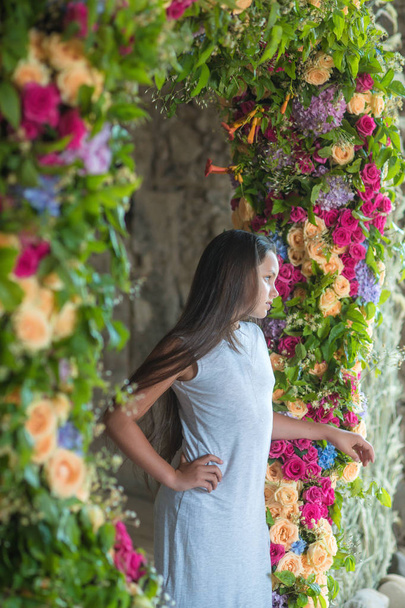 Teenage girl with long hair stand in flower arch, beauty - Photo, image
