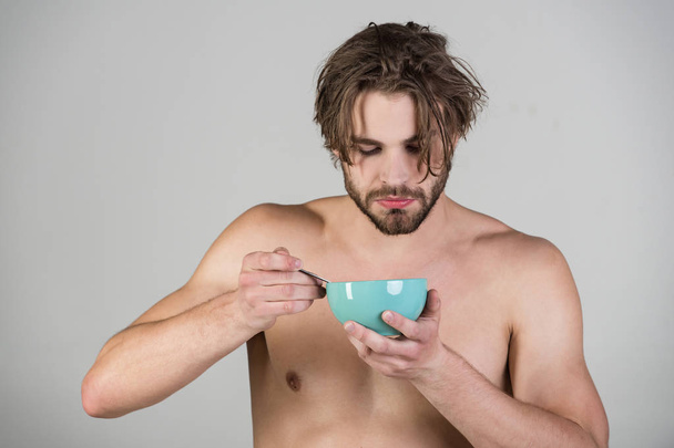 Man with wet hair eat breakfast on grey background - Zdjęcie, obraz