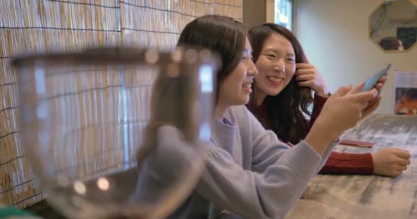 Cute girls using smartphones in cafe - Video