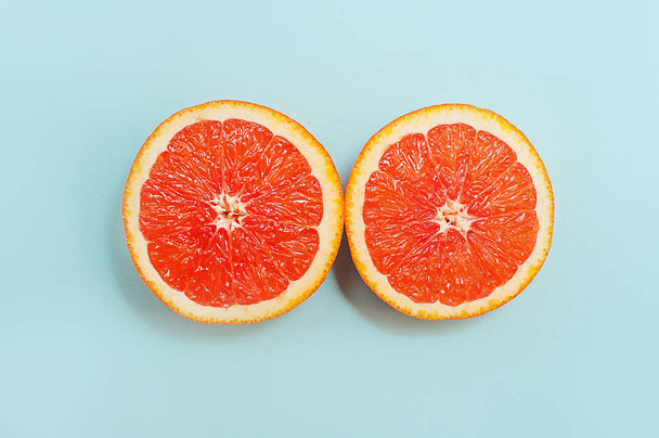 Minimal style, creative layout orange and grapefruit. Flat lay. Food concept. Half an orange on turquoise background. - Photo, image
