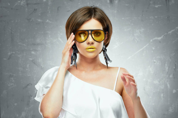 beautiful young model with yellow lipstick on lips wearing sunglasses and white shirt with naked shoulder  - Foto, Bild