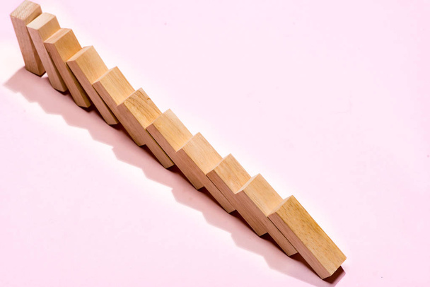 Domino block. Dominoes continuous toppled on pink background. - Photo, Image