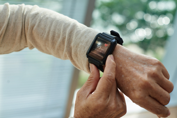 Close-up shot of wrinkled female hand with modern fitness tracker, blurred background - Φωτογραφία, εικόνα