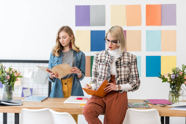 красивые редакторы журналов делают бумажную работу в современном офисе с цветовой палитрой
 - Фото, изображение