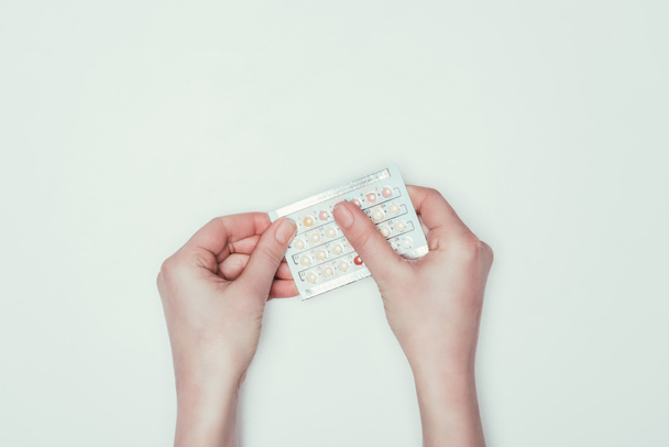 cropped shot of woman holding contraceptive pills in hands isolated on grey - Foto, immagini