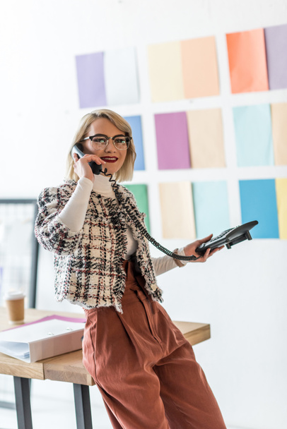 businesswoman talking on phone in modern office with color palette on wall - Photo, Image