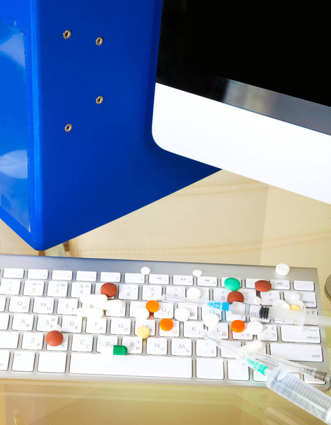 Doctor workplace with pills and glasses with keyboard  - Photo, Image