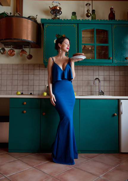Redhead woman in blue dress holding birthday chocolate cake at kitchen - Fotoğraf, Görsel