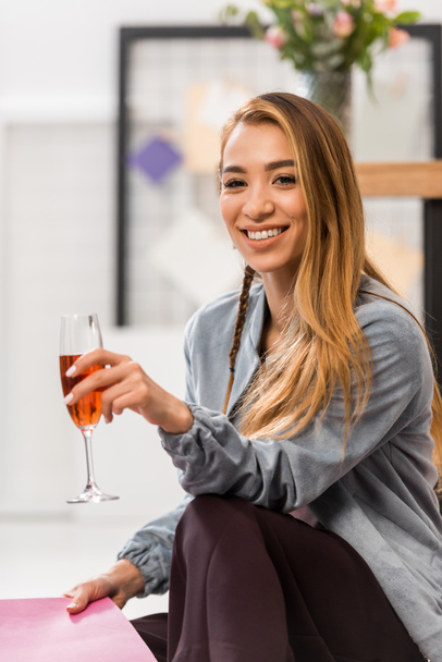 Азиатская девушка празднует с бокалом шампанского в современном офисе
 - Фото, изображение
