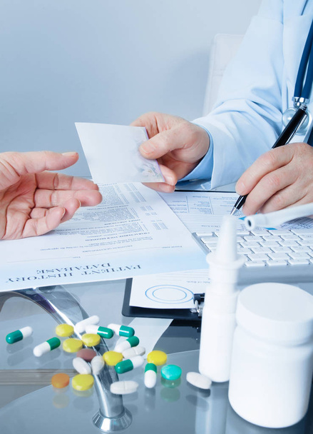 doctor giving recipe to patient while writing prescription at workplace - Photo, Image