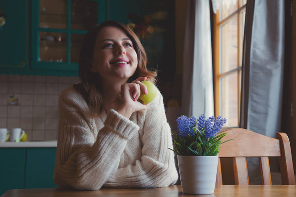 Kızıl saçlı kadın mutfakta masada oturan apple ile portresi. - Fotoğraf, Görsel