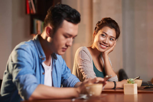 Muotokuva hymyilevä aasialainen nainen katselee muukalainen mies kahvilassa
 - Valokuva, kuva