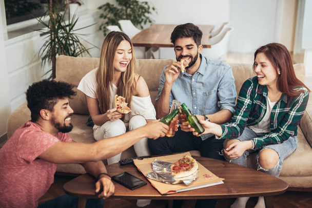 Grupa młodych przyjaciół jedzących pizzę.Strona domowa.Koncepcja Fast food. - Zdjęcie, obraz