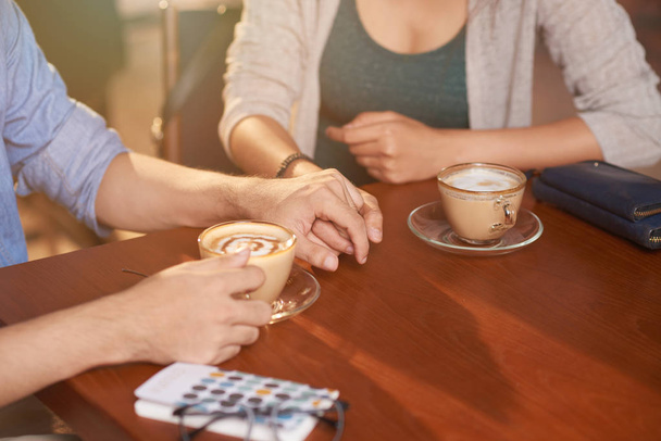 Zbliżenie, para, trzymając się za ręce z opieki i wsparcia na daty w kawiarni - Zdjęcie, obraz