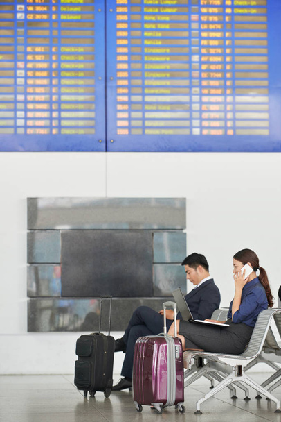Side view portrait of modern Asian business people in airport with big suitcases - Photo, Image