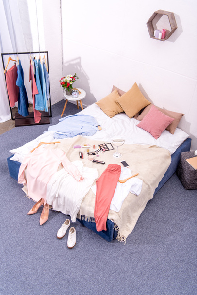 magas szög kilátás belső modern hálószoba tele különböző női ruha és smink kellékek fogas ágy - Fotó, kép
