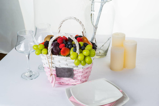 Still life: basket with fruits and berries, coffee cups and candles - Valokuva, kuva