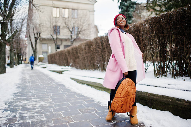 African american girl in red hat and pink coat with backpack at  - Foto, imagen