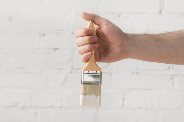 cropped image of man holding brush in white paint - Fotoğraf, Görsel