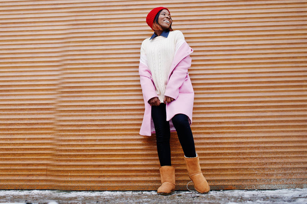 African american girl in red hat and pink coat against orange sh - Foto, immagini