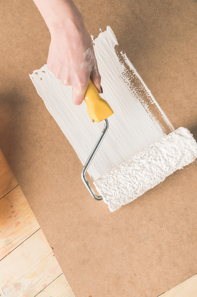 cropped image of woman painting plywood with paint roll brush - Foto, immagini