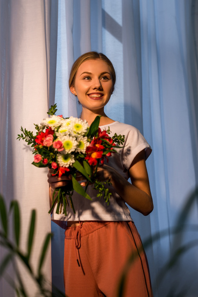 young woman with beautiful bouquet against window - Foto, afbeelding