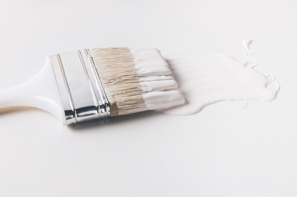 one paint brush in white paint on surface isolated on white - Φωτογραφία, εικόνα